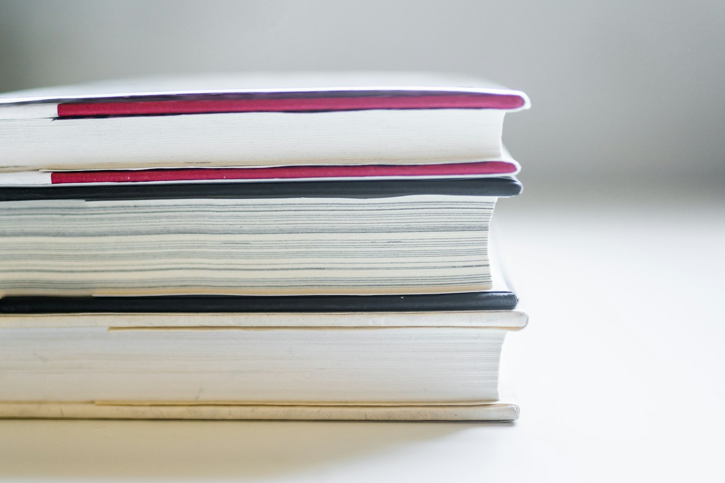 A neat stack of books or notebooks on a shelf.